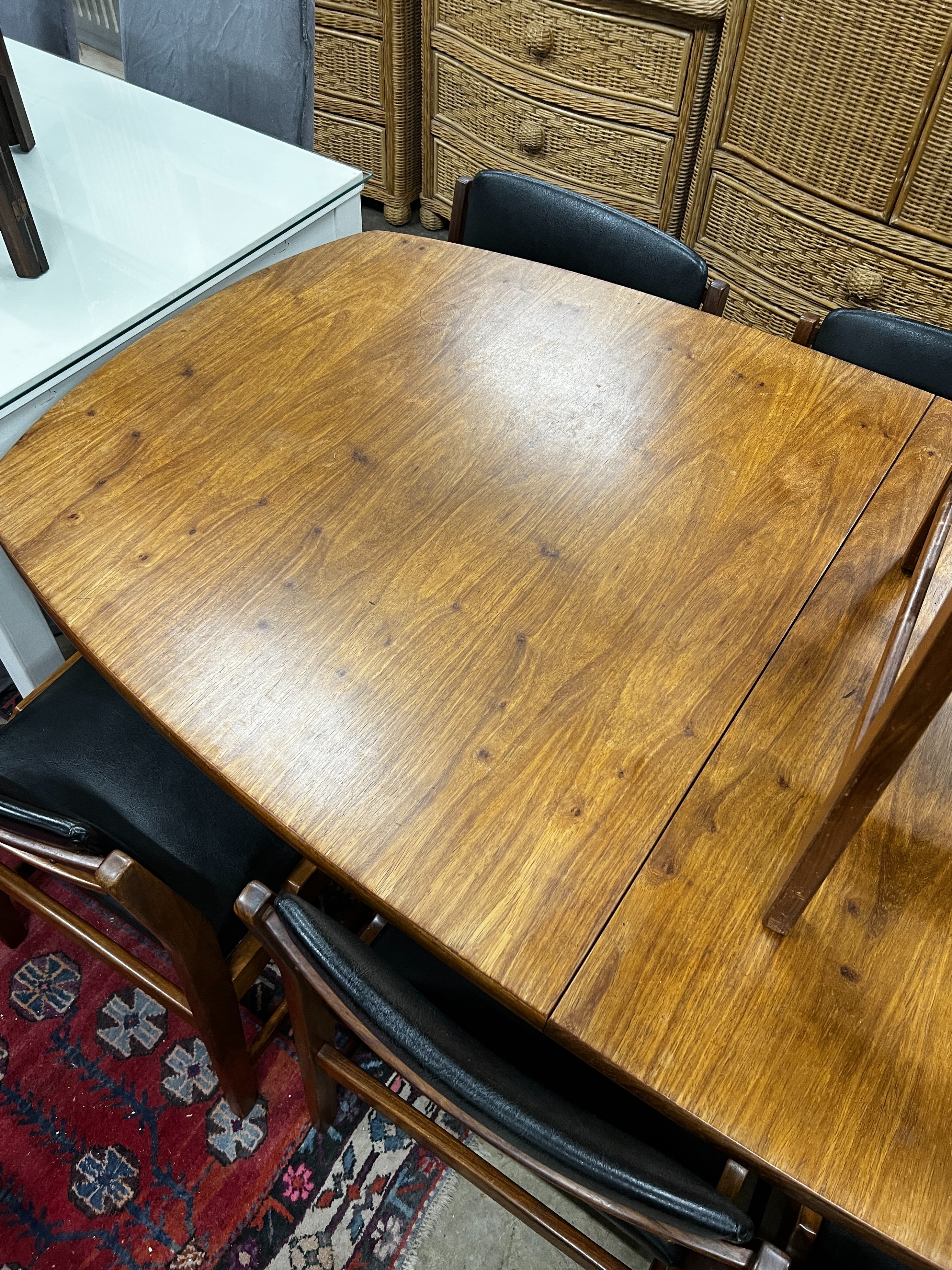 A mid century Novocraft teak dining suite comprising extending dining table 230cm extended, width 97cm, height 74cm, seven black leatherette chairs, one with arms and a sideboard width 178cm.